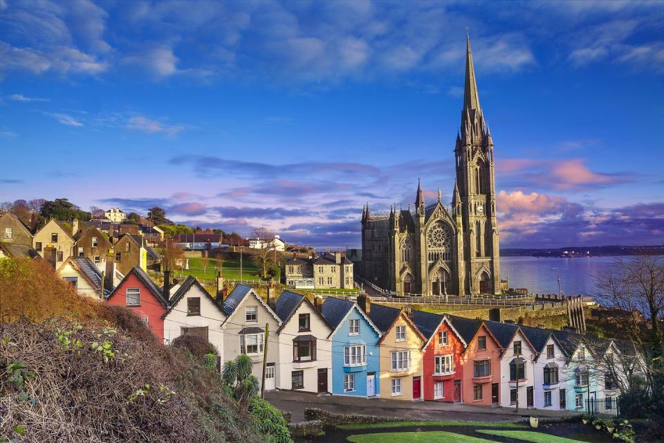 cobh county cork, ireland with a row of colorful houses with cobh catherdral against a dramatic skyline