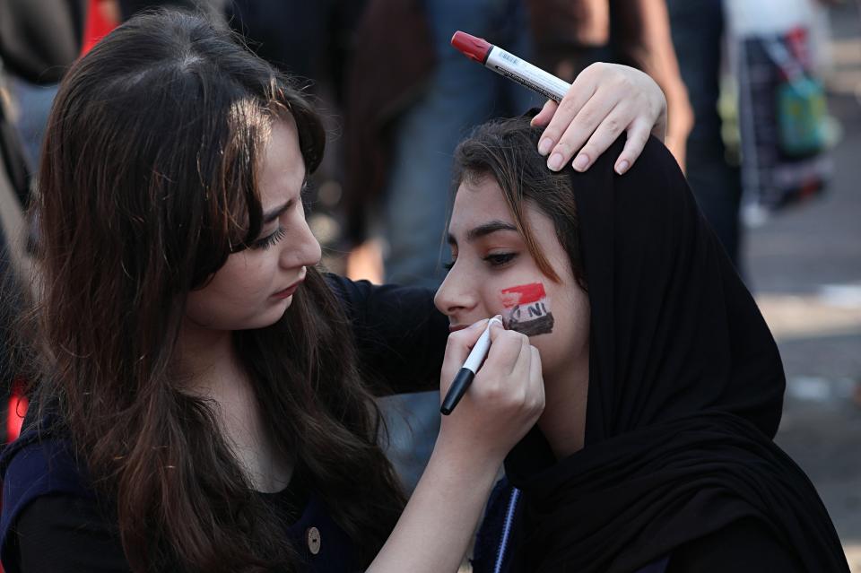 A protester gets her face painted with the colors of the Iraqi flag during ongoing anti-government protests at Tahrir square in Baghdad, Iraq, Thursday, Oct. 31, 2019. (AP Photo/Hadi Mizban)