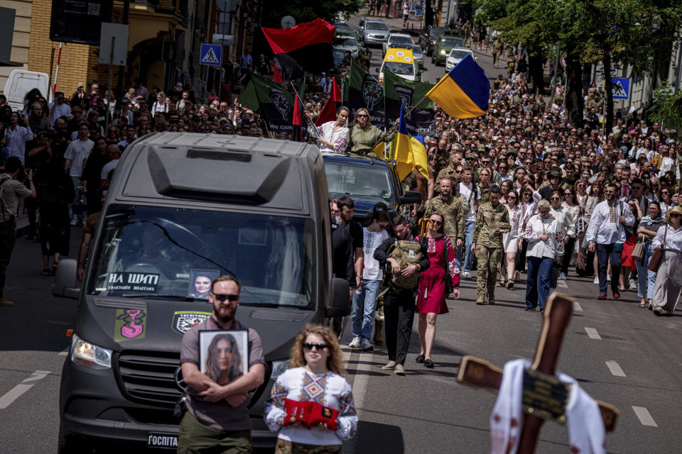 People walk along Mykhailivska Street during memorial service for the Ukrainian journalist and volunteer combat medic Iryna Tsybukh at St. Michael's Golden-Domed Monastery in Kyiv, Ukraine, Sunday, June 2, 2024. Nearly 1,000 people attended a ceremony Sunday honoring the memory of Ukrainian journalist Iryna Tsybukh, who was killed in action while serving as a combat medic a few days before her 26th birthday. Tsybukh was killed while on rotation in Kharkiv area, where Russia started its offensive nearly a month ago. (AP Photo/Evgeniy Maloletka)