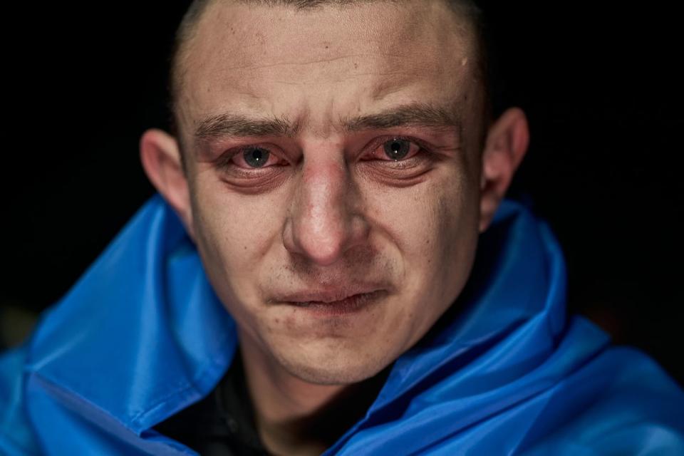 A man wears a Ukrainian flag during a night-time exchange of prisoners of war in Ukraine on Feb. 8, 2024. About 100 soldiers of the Armed Forces of Ukraine were returned from Russian captivity in the Feb. 8 exchange. (Kostiantyn Liberov/Libkos/Getty Images)