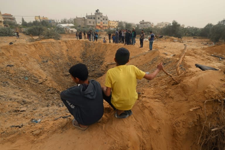 Two Palestinian boys look at a huge crater following an overnight Israeli bombardment in Rafah, southern Gaza Strip (MOHAMMED ABED)