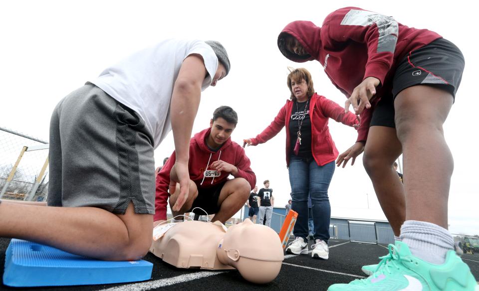 New Prairie High School educator Tonya Aerts, second from right, helps instruct track team members Camden Ziglar, left, Miguel Mendez, center, and Isaiah King on March 2, 2023, during a “sudden cardiac arrest” drill on the track. The girls' and boys' track teams at the Indiana high school underwent a drill where they performed CPR and practiced using an automatic external defibrillator (AED).