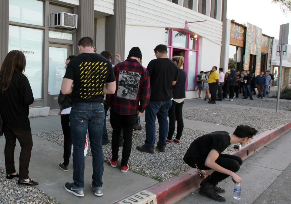 Visitors, left, form a line at the Stephen Cohen Gallery to enter an exhibition called "#IAMSORRY" by actor Shia LaBeouf, while on the right people line up for another art exhibit, "#IAMSORRYTOO," by Jerry O'Connell at Artspace Warehouse in Los Angeles on Wednesday, Feb. 12, 2014. Seated at a small table, wearing a disheveled tuxedo and the paper bag with some eye holes cut out and the words "I AM NOT FAMOUS ANYMORE" scrawled in black ink across it, LaBeouf began his planned seven-hour, seven-day stint inside the small gallery on Tuesday, Feb. 11, 2014. Inside Artspace Warehouse, O'Connell donned a paper bag with the words "SUPER FAMOUS" on it. (AP Photo/Richard Vogel)