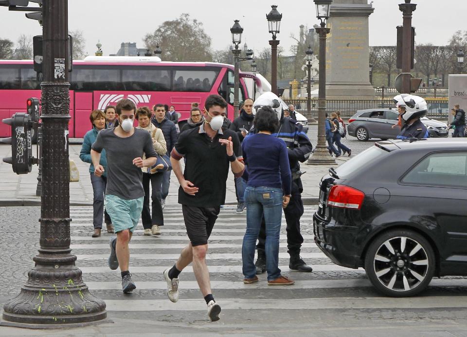 FILE - In this Monday, March 17, 2014 file photo, two joggers wearing protective masks run past a police officer controlling a vehicle on the Concorde square in Paris. Air pollution kills about 7 million people worldwide every year according to a new report from the World Health Organization published Tuesday March 25, 2014. The agency said air pollution triggers about 1 in 8 deaths and has now become the single biggest environmental health risk, ahead of other dangers like second-hand smoke. (AP Photo/Remy de la Mauviniere, File)