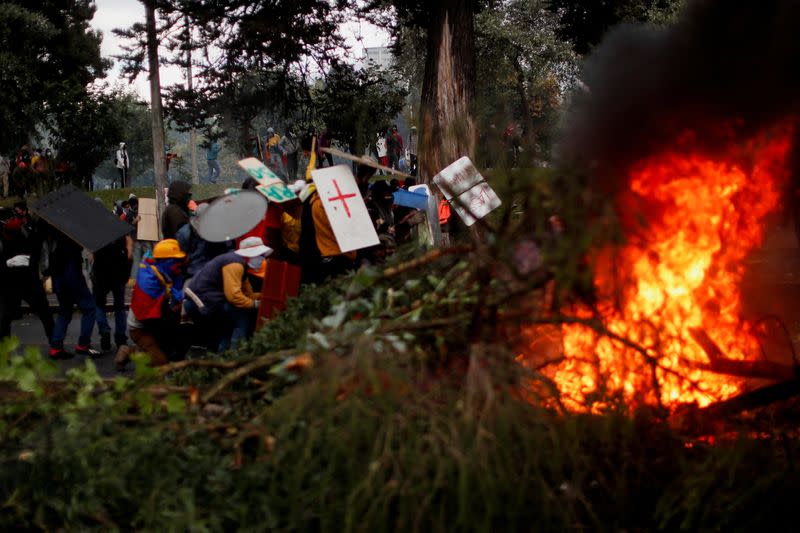 Se ven ramas quemándose mientras los manifestantes usan escudos improvisados durante una protesta antigubernamental, en Quito, Ecuador