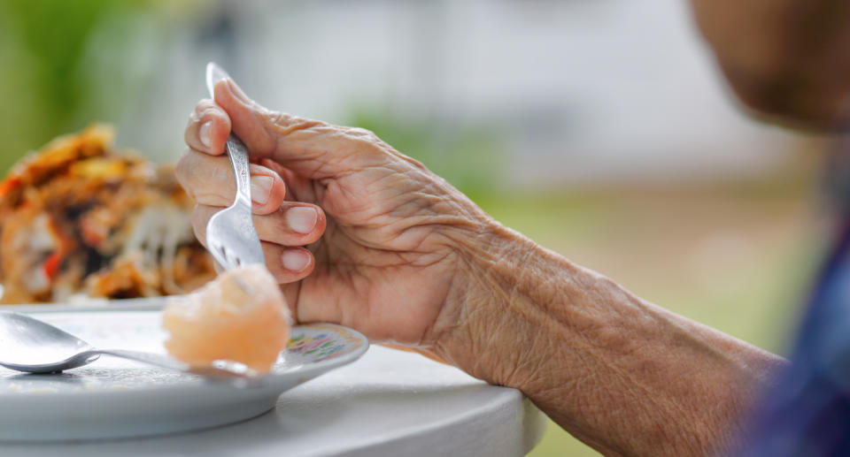 Image shows aged person eating (stock photo).