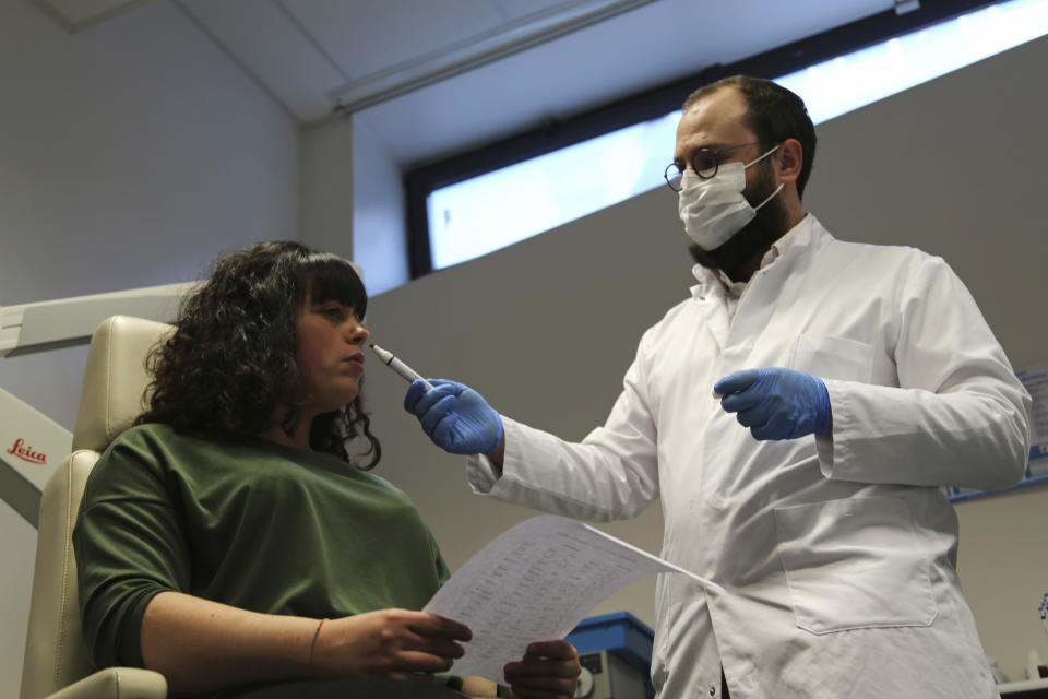 Dr. Clair Vandersteen, right, wafts a tube of odors under the nose of a patient, Gabriella Forgione, during tests in a hospital in Nice, southern France, Monday, Feb. 8, 2021, to help determine why she has been unable to smell or taste since she contracted COVID-19 in November 2020. A year into the coronavirus pandemic, doctors and researchers are still striving to better understand and treat the accompanying epidemic of COVID-19-related anosmia — loss of smell — draining much of the joy of life from an increasing number of sensorially frustrated longer-term sufferers like Forgione. (AP Photo/John Leicester)
