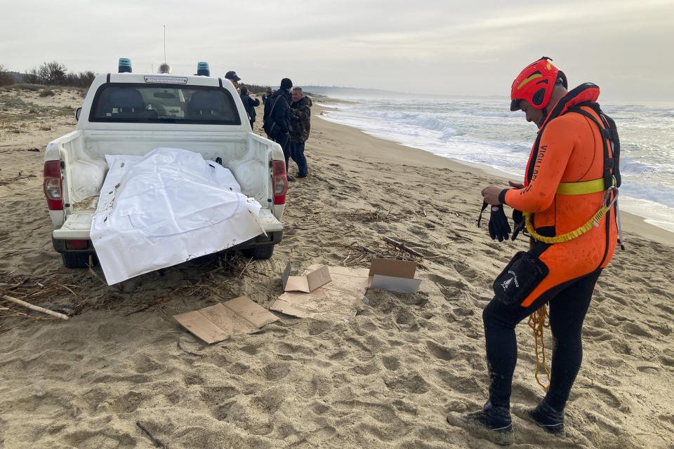 A rescuer stands next to a vehicle with the body of a victim from Sunday's shipwreck off the Calabrian coast, at a beach near Cutro, southern Italy, Monday, Feb. 27, 2023. Nearly 70 people died in last week's shipwreck on Italy's Calabrian coast. The tragedy highlighted a lesser-known migration route from Turkey to Italy for which smugglers charge around 8,000 euros per person. (AP Photo/Paolo Santalucia, File)