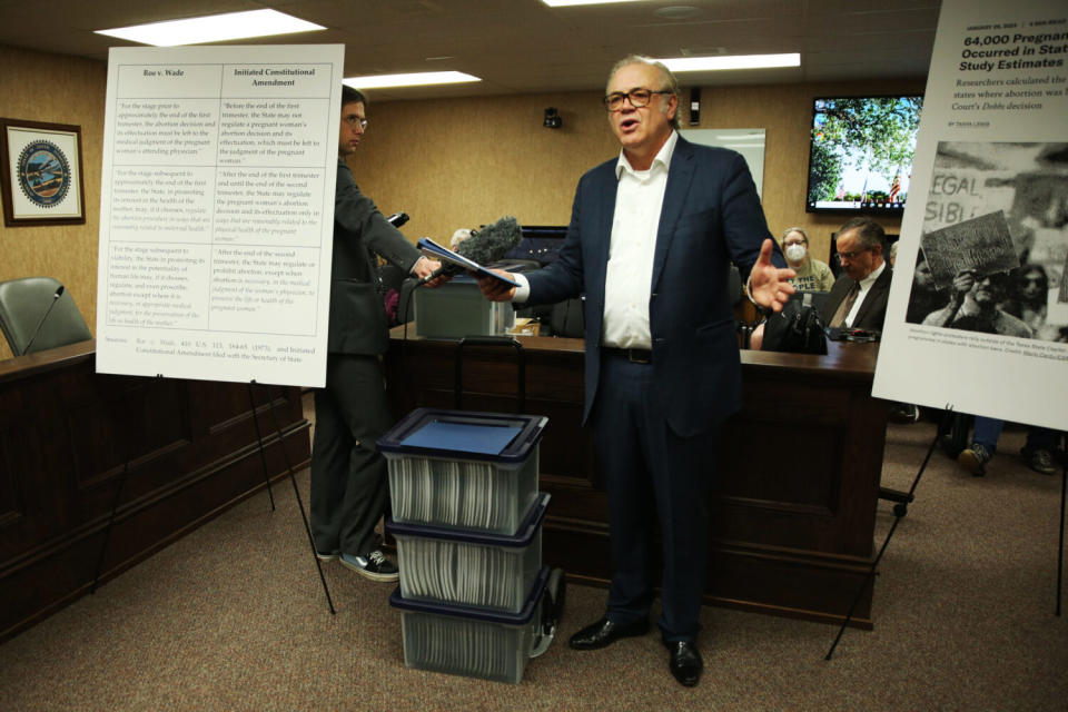 Dakotans for Health Executive Director Rick Weiland, standing beside copies of petition sigantures, speaks to the press Feb. 7, 2024, at the Capitol in Pierre about an initiated constitutional amendment to enshrine abortion rights in the state constitution. (Makenzie Huber/South Dakota Searchlight)