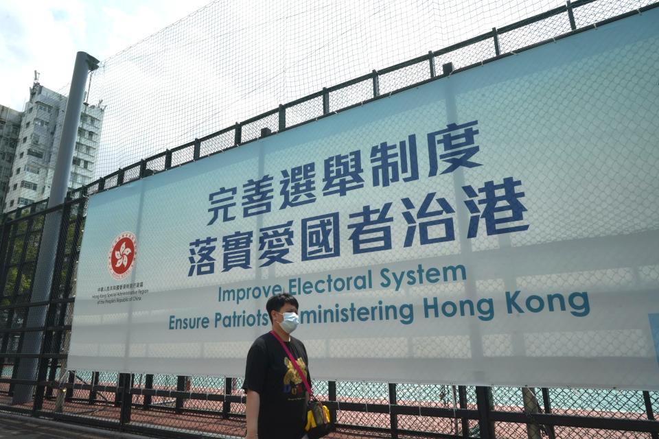 A man walks past a government advertisement to promote the new Hong Kong electoral system reform, in Hong Kong, March 30, 2021. China's top legislature approved amendments to Hong Kong's constitution on Tuesday that will give Beijing more control over the make-up of the city's legislature. (AP Photo/Kin Cheung)