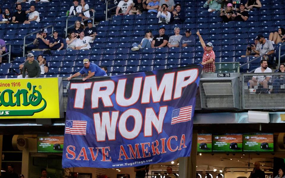 Two supporters of former US President Donald Trump display a banner -  JASON SZENES/Shutterstock 