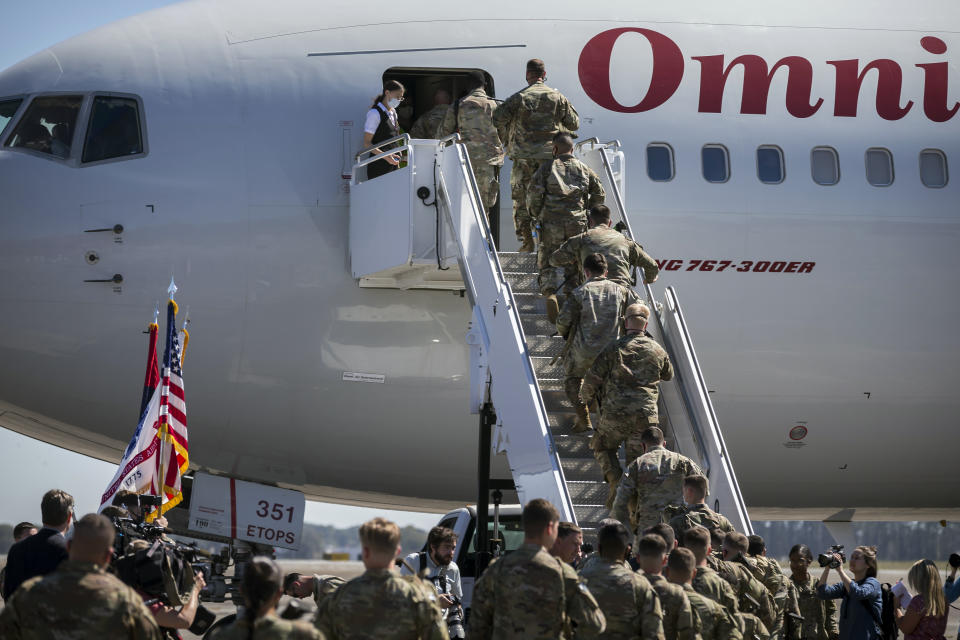 A honor guard send stand at attention as over 180 soldiers with the U.S. Army 3rd Infantry Division, 1st Armored Brigade Combat Team climb the stairs to a charter airplane at Hunter Army Airfield during their deployment to Germany, Wednesday March 2, 2022 in Savannah, Ga. The division is sending 3,800 troops as reinforcements for various NATO allies in Eastern Europe. (Stephen B. Morton /Atlanta Journal-Constitution via AP)