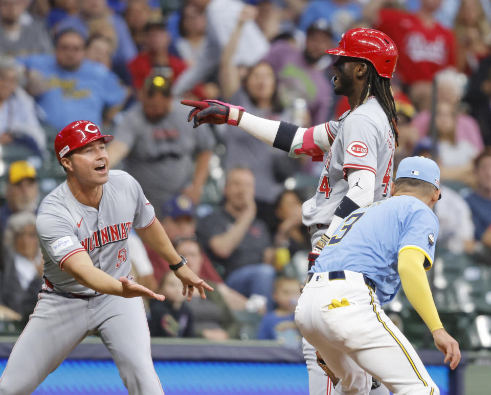 Cincinnati Reds' Elly De La Cruz, top right, reacts with third base coach J.R. House, left, after hitting a triple during the fifth inning of a baseball game against the Milwaukee Brewers, Friday, June 14, 2024, in Milwaukee. (AP Photo/Jeffrey Phelps)