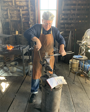 Ken Pilarczyk works a piece of metal into a candleholder at the Saurer Blacksmith Shop at Sonnenberg Village during a 2019 festival.