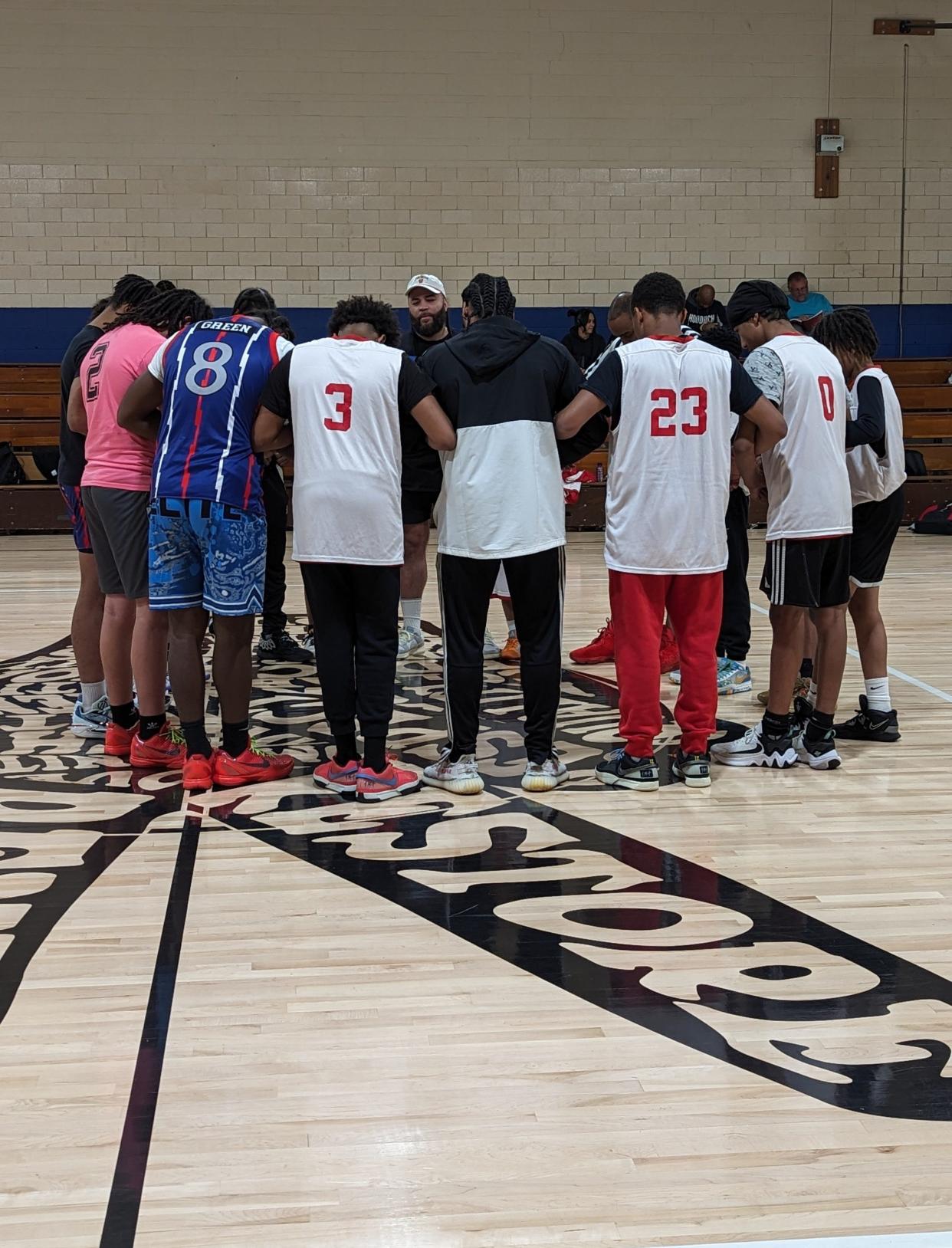 Nate Chester (center), executive director of the Martin Center in Canton leads a prayer prior to a basketball game sponsored by Taking The Crown, a faith-based sports outreach for teen boys.