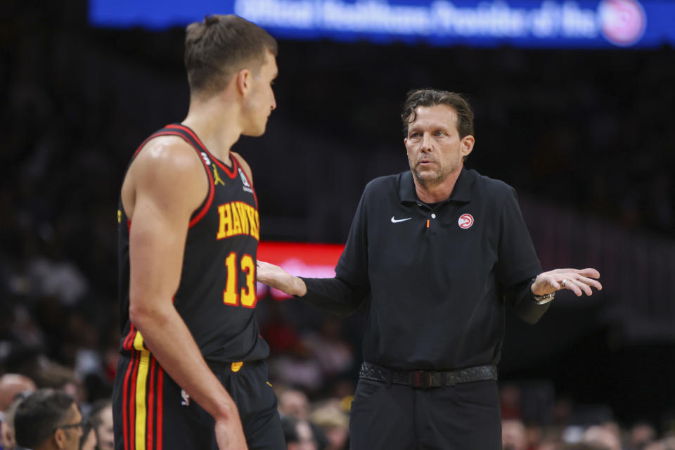 Atlanta Hawks head coach Quin Snyder, right, talks to guard Bogdan Bogdanovic, left, in the first half of an NBA basketball game against the Minnesota Timberwolves, Monday, March 13, 2023, in Atlanta. (AP Photo/Brett Davis)