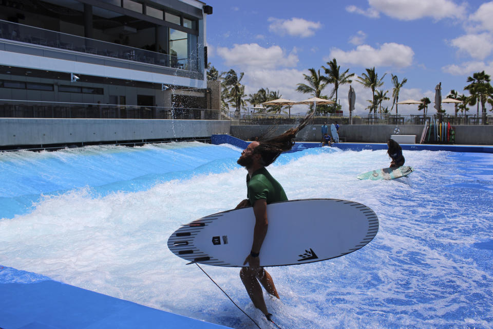 Ikaika Kaulukukui flips his hair after emerging from surfing at a wave pool in Ewa Beach, Hawaii, Tuesday, May 9, 2023. A prominent Hawaiian waterman wants to build another Hawaii wave pool facility using the latest technology to simulate the ideal conditions top-notch surfers need to stay competitive. But some people, including fellow Hawaiians, want to stop the project and say it is a waste of water and pointless in Hawaii, the birthplace of surfing, where a good break is often just minutes away. (AP Photo/Jennifer Sinco Kelleher)