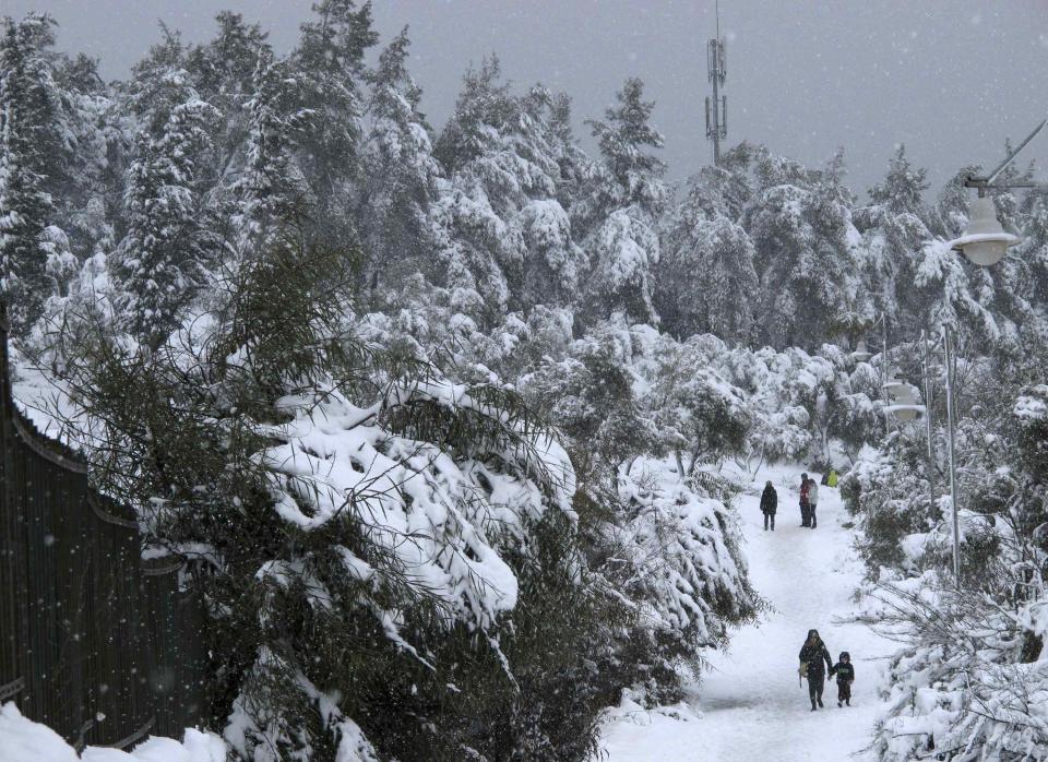 People walk through a park as snow falls in Jerusalem