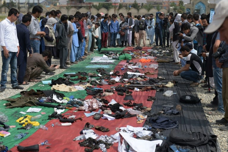 Relatives and friends inspect shoes and other belongings of those who were killed in the twin suicide attack, gathered on the ground at a mosque in Kabul on July 24, 2016