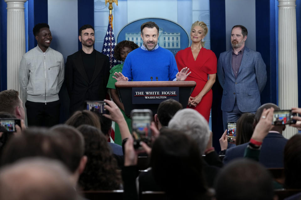 Jason Sudeikis, fourth from left, who plays the title character in the Apple TV+ series “Ted Lasso”, speaks as he joins White House press secretary Karine Jean-Pierre, third from left, and fellow cast members, from left, Toheeb Jimoh, Brett Goldstein, Hannah Waddingham, and Brendan Hunt, during the daily press briefing at the White House in Washington, Monday, March 20, 2023. (AP Photo/Susan Walsh)