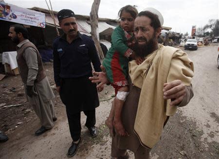 A resident carries his daughter, who was injured in a bomb blast, as they evacuate from a site of a bomb blast on the outskirts of Peshawar March 14, 2014. EUTERS/Fayaz Aziz