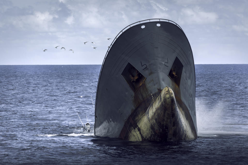 The hull of a ship, upended as the vessel appears to sink into the ocean.