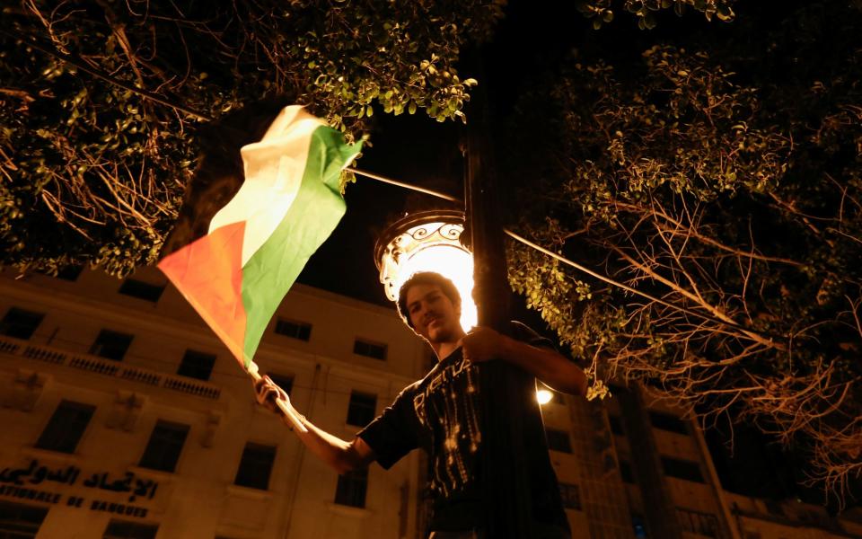 A man waves a Palestinian flag as people gather during a protest after hundreds of Palestinians were killed in a blast at Al-Ahli hospital in Gaza