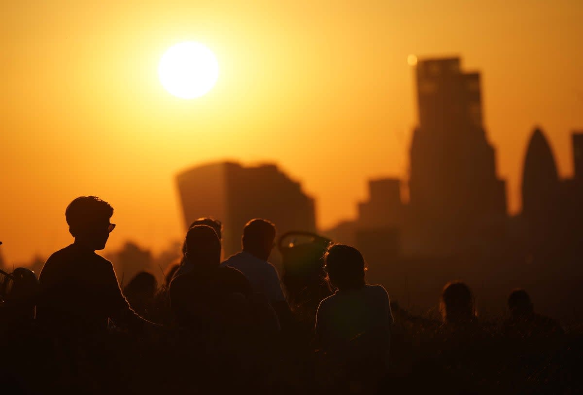 People in Greenwich Park watch the sun set over London in July 2021 (Yui Mok/PA) (PA Archive)