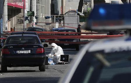 A police forensic expert searches for evidence outside the local offices of far-right Golden Dawn party, following last night's shooting, in a northern suburb of Athens November 2, 2013. REUTERS/John Kolesidis