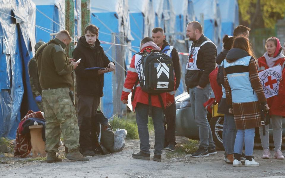 A young man evacuated from the Azovstal steel plant in Mariupol stands surrounded by service members of pro-Russian troops and members of the International Committee of the Red Cross (ICRC) at a temporary accommodation centre in the village of Bezimenne, in the Donetsk Region of Ukraine on May 6, 2022. - Alexander Ermochenko/Reuters