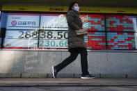 A woman wearing a protective mask walks in front of an electronic stock board showing Japan's Nikkei 225 index at a securities firm Wednesday, Dec. 29, 2021, in Tokyo. Asian shares mostly slipped Wednesday, as worries lingered about the coronavirus omicron variant's potential damage to the regional economy following mixed cues from Wall Street. (AP Photo/Eugene Hoshiko)