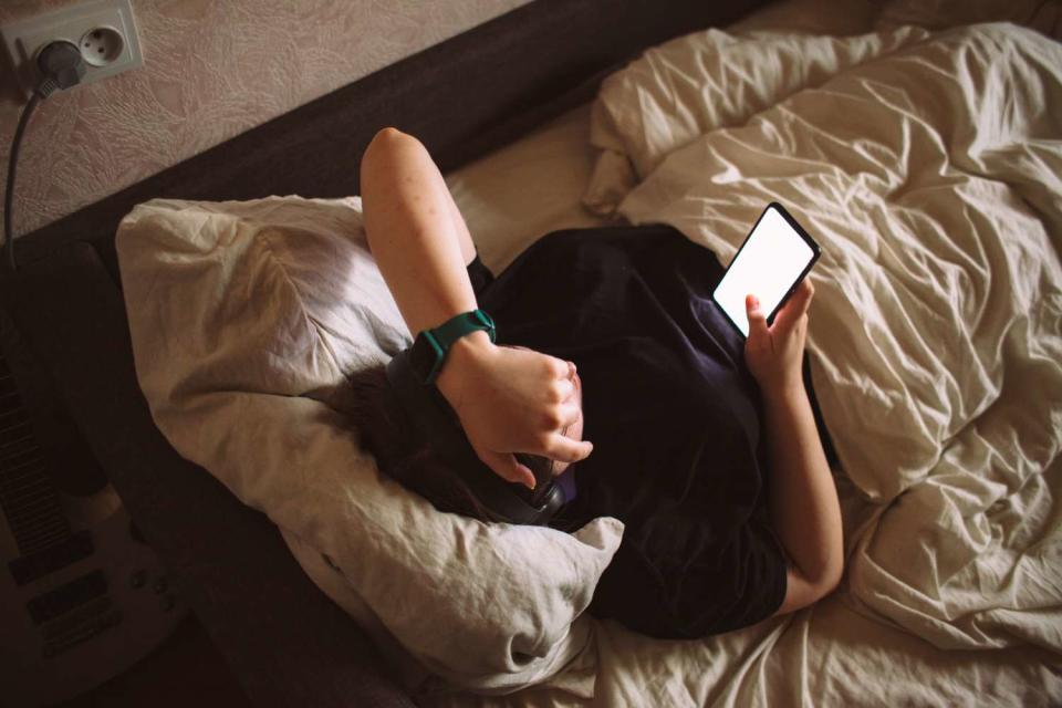 <p>Getty</p> Stock image of a person reading from their smartphone before bedtime.