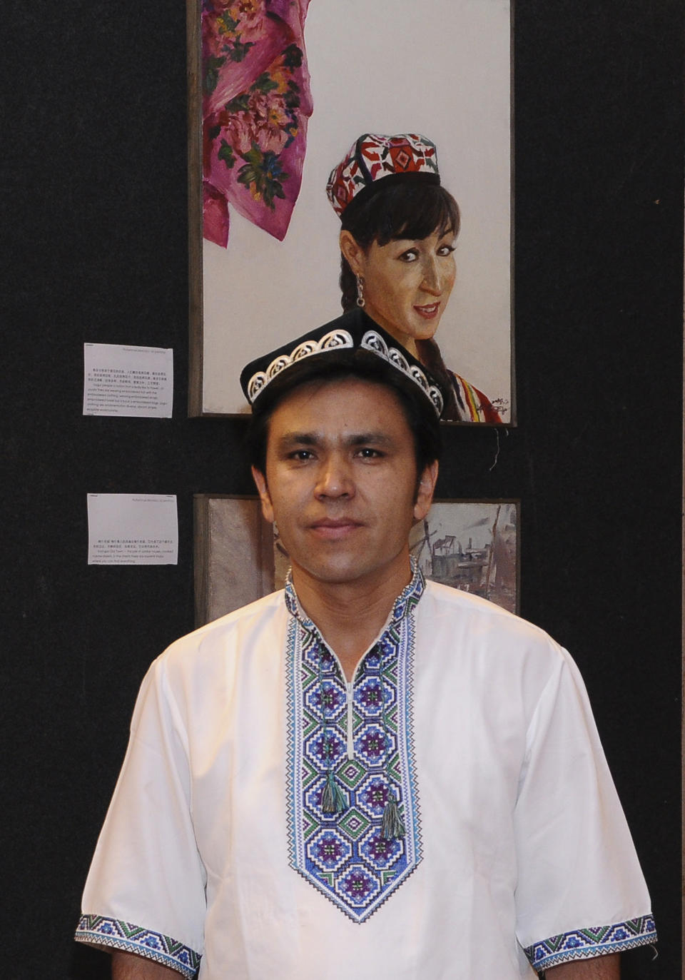 In this photo taken March 4, 2014 and provided March 18, 2014 by Daniel Liau, Maimaitijiang Abula, an artist, poses for a picture in front of pieces of his work on display at an exhibition of Chinese art in Kuala Lumpur, just days before he boarded Malaysia Airlines flight MH370 to Beijing that has since gone missing. Abula, a 34-year-old art teacher from China’s far west Xinjiang region, home to China’s Turkic-speaking Uighur ethnic minority, was abroad for the first time and part of the group of painters and calligraphers in Malaysia for an exhibition. (AP Photo)