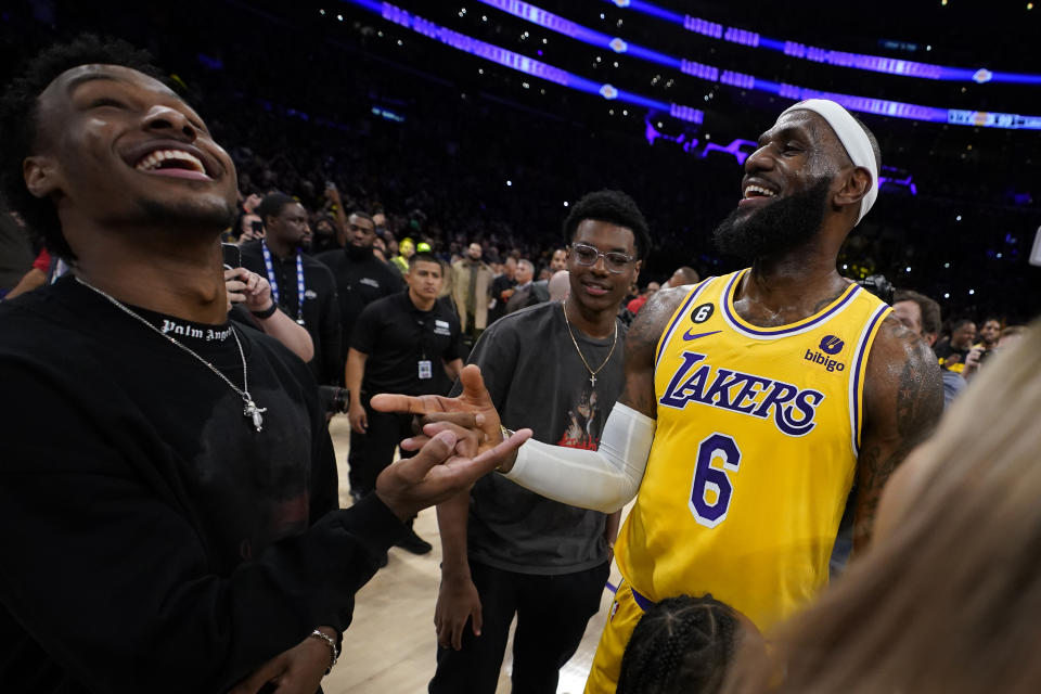 Los Angeles Lakers forward LeBron James, right, celebrates with his sons Bronny, left, and Bryce after passing Kareem Abdul-Jabbar to become the NBA's all-time leading scorer during the second half of an NBA basketball game against the Oklahoma City Thunder Tuesday, Feb. 7, 2023, in Los Angeles.(AP Photo/Ashley Landis)