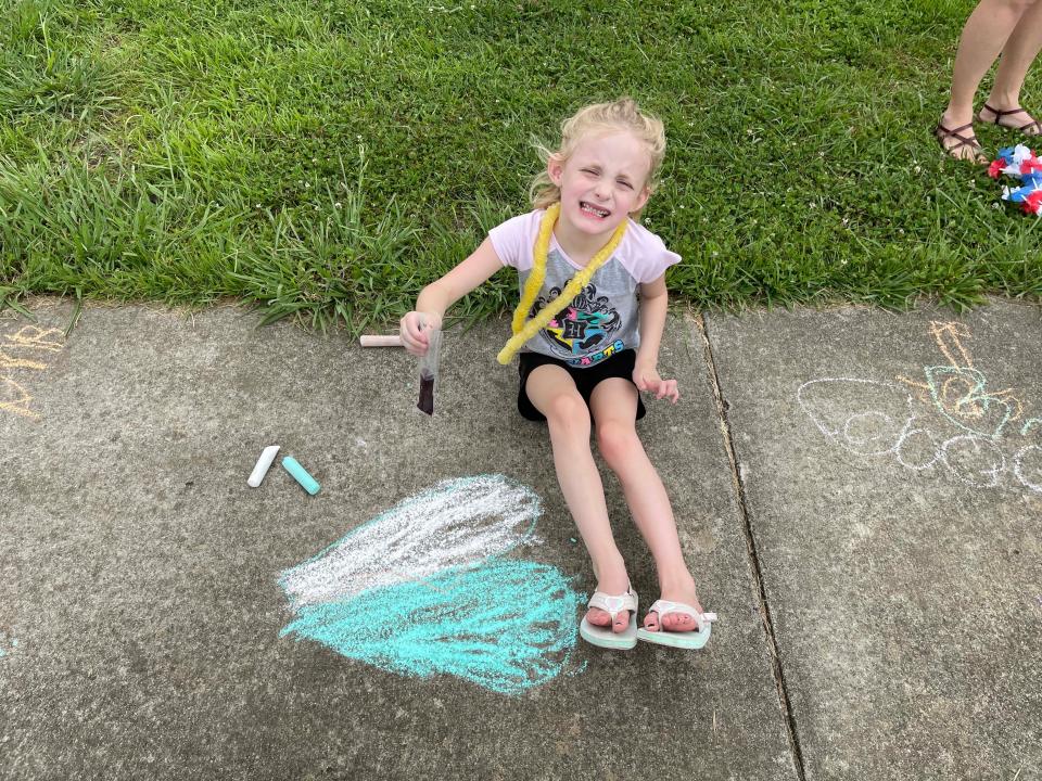 Kindergartener Alexa Caylor shows off her brightest smile along with her sidewalk chalk art at the annual Hardin Valley Elementary School Popsicle Party held at the school Sunday, Aug. 14, 2022.