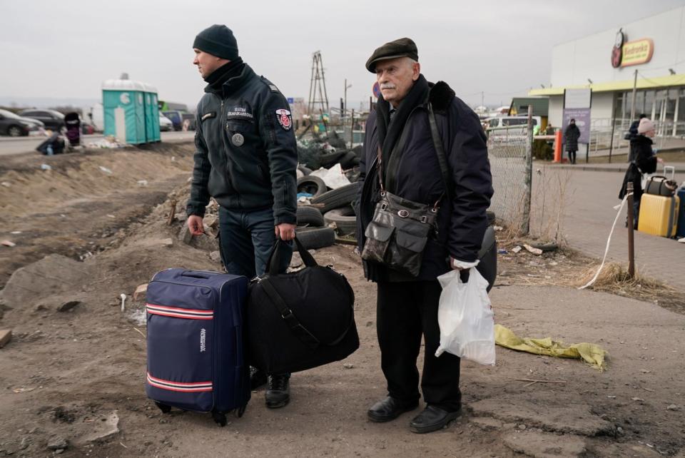 A customs agent helps Anatoly Scherbak after crossing into Medyka, Poland from Ukraine, Wednesday March 2, 2022.