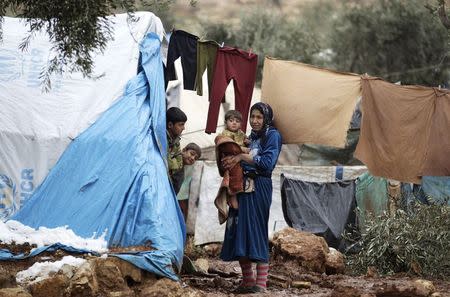 An internally displaced family stand by their tent inside Atma refugee camp beside the Syrian-Turkish border in Northern Idlib countryside January 11, 2015. REUTERS/Khalil Ashawi