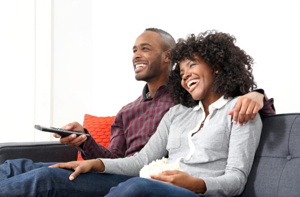 A couple is watching TV on the sofa.