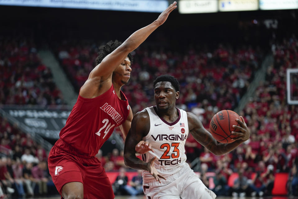 Virginia Tech guard Tyrece Radford (23) drives toward the basket around Louisville forward Dwayne Sutton (24) during the first half of an NCAA college basketball game, Sunday, March 1, 2020, in Louisville, Ky. (AP Photo/Bryan Woolston)