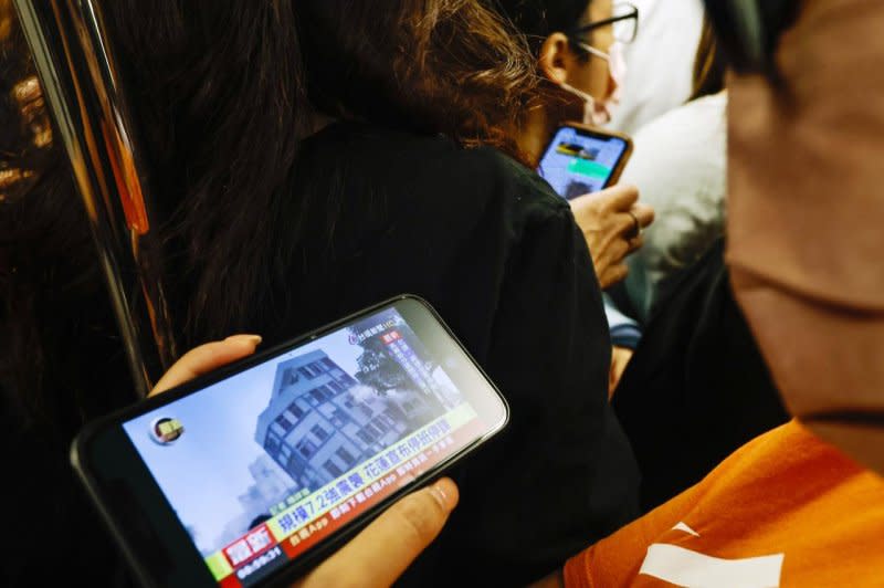 A passenger on a subway train watches a TV news report Wednesday about a residential building collapsed in Hualien following a magnitude 7.4 earthquake, in Taipei, Taiwan. The quake struck Taiwan earlier that morning with an epicenter 11 miles south of Hualien City, according to the U.S. Geological Survey. Photo by Daniel Ceng/EPA-EFE