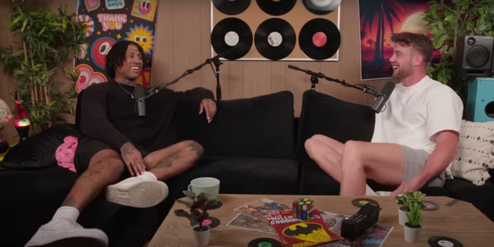 Dom Gabriel and Harry Jowsey laughing while sitting on a black couch