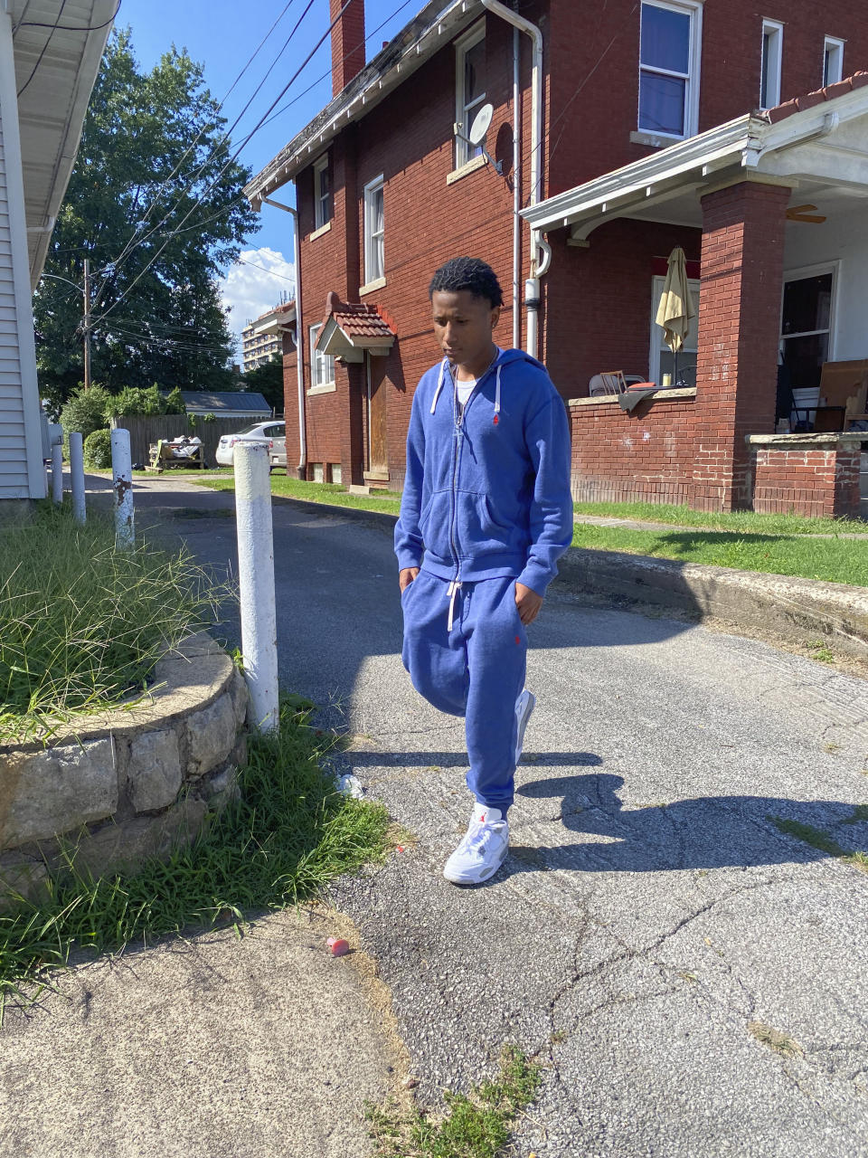 In this Sept. 9, 2021, photo X'Zane Watts walks out of the alley in Charleston, W.Va. where he was chased in 2017 at age 15 by undercover officers who followed him into his home and pointed a gun at his head. Police said that he appeared to fit the description of a burglary suspect. The family settled with the city for an undisclosed sum. (AP Photo/Colleen Long)