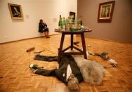 A security guard at the San Carlos museum in Mexico City sits in her chair behind a piece by British artist Damien Hirst titled "Adam and Eve under the table" between two 16th century paintings October 6, 2006.