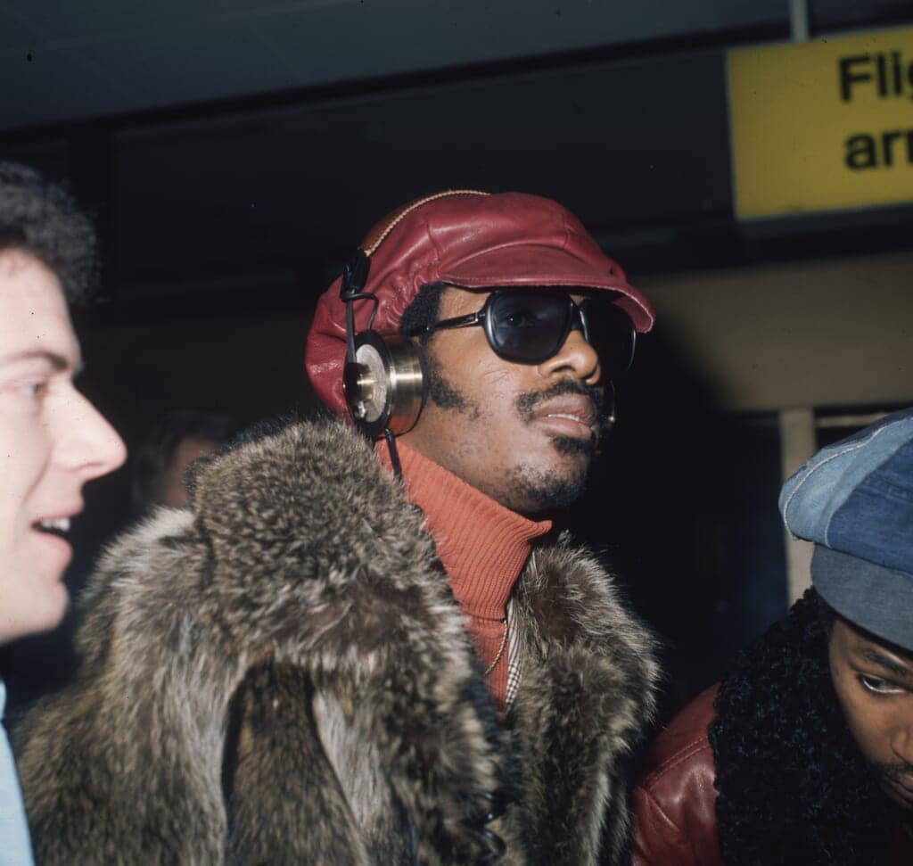 Stevie Wonder (center), shown here at the London Airport, has influenced myriad artists across musical genres in his long and storied career. (Photo by Fox Photos/Getty Images)