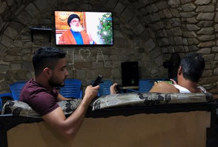 Men watch Lebanon's Hezbollah leader Sayyed Hassan Nasrallah speak on TV inside a coffee shop in Sidon