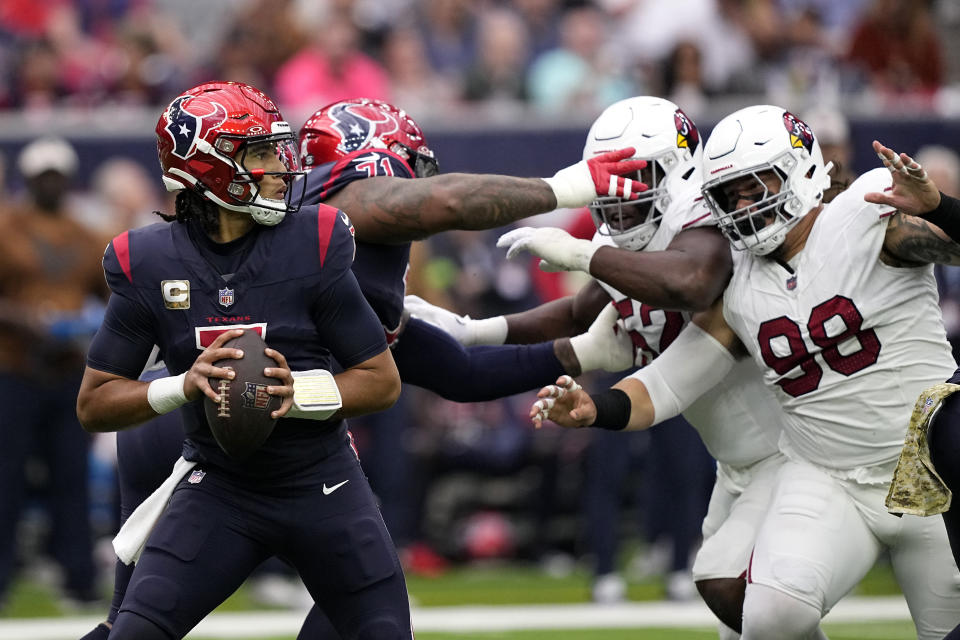 Houston Texans quarterback C.J. Stroud, left, prepares to throw a pass under pressure from Arizona Cardinals defensive tackle Roy Lopez (98) in the first half of an NFL football game in Houston, Sunday, Nov. 19, 2023. (AP Photo/David J. Phillip)