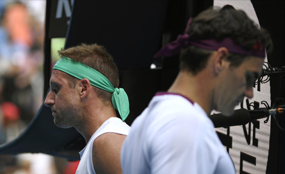 Tennys Sandgren, left, of the U.S. and Switzerland's Roger Federer pass as they change ends during their quarterfinal match at the Australian Open tennis championship in Melbourne, Australia, Tuesday, Jan. 28, 2020. (AP Photo/Andy Brownbill)