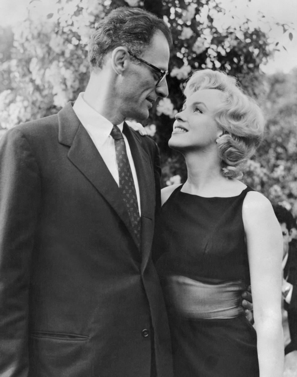 Marilyn Monroe and Arthur Miller smile at each other outside of their home
