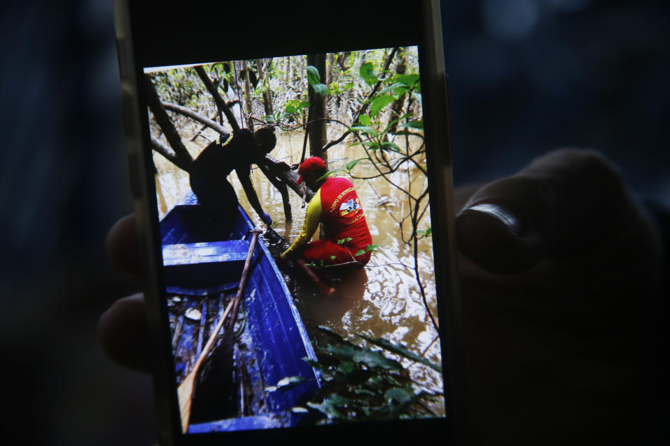 A firefighter holds a cell phone with a picture showing the moment when a backpack was found during a search for Indigenous expert Bruno Pereira and freelance British journalist Dom Phillips in Atalaia do Norte, Amazonas state, Brazil, Sunday, June 12, 2022. Divers from Brazil's firefighters corps found a backpack and laptop Sunday in the remote Amazon area where Pereira and Phillips went missing a week ago, firefighters said. (AP Photo/Edmar Barros)