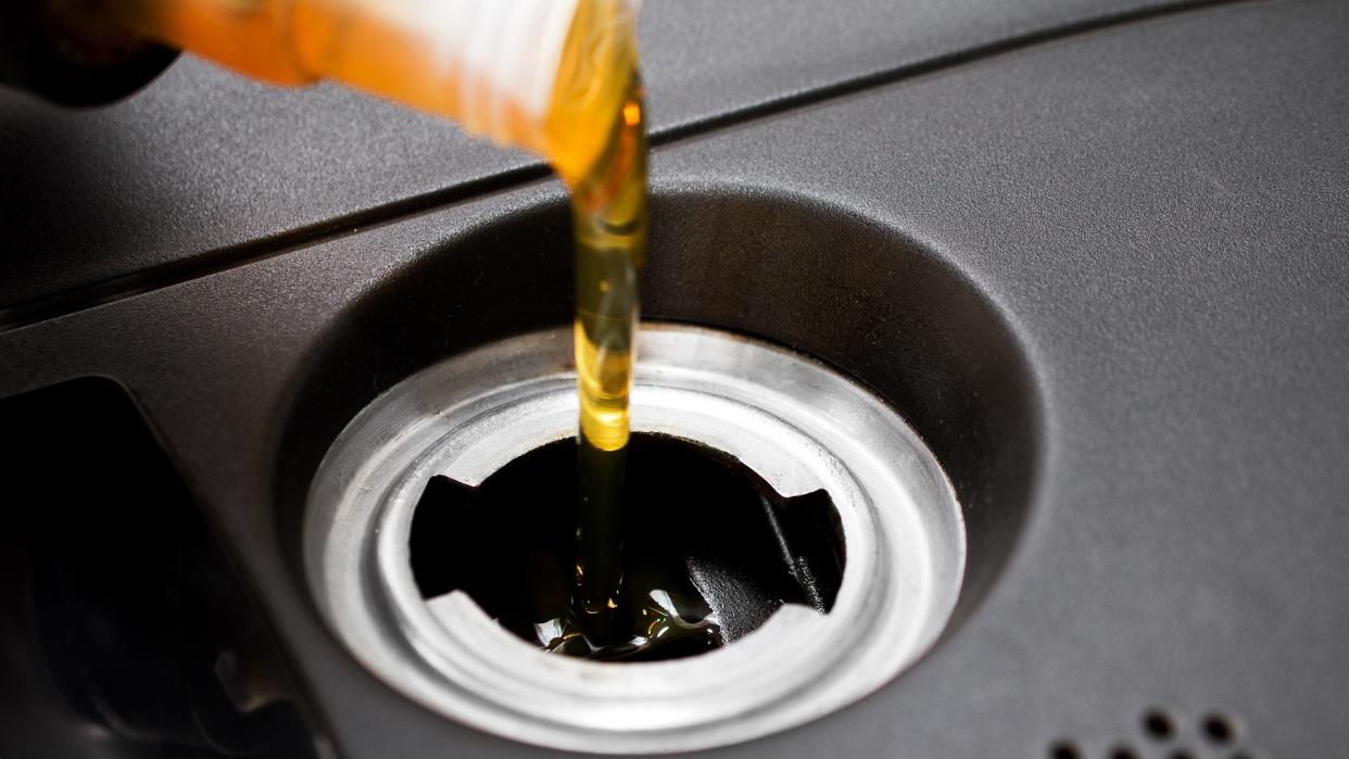 mechanic replenishing oil reserve in car